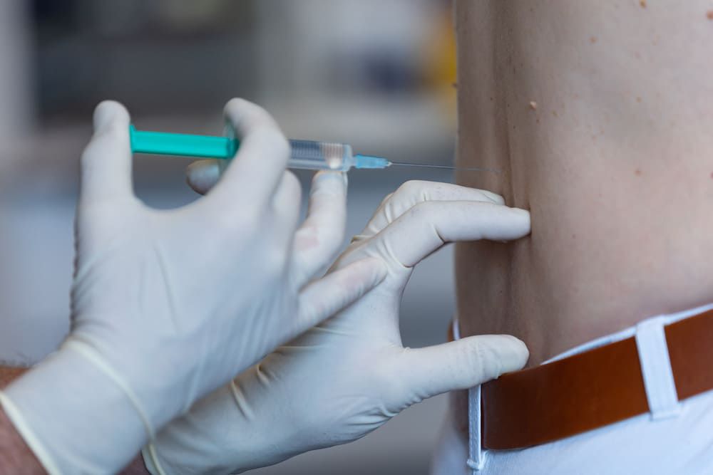 Nahansicht von Dr. Hasch Händen bei einer Gelenkinjektion im Rücken