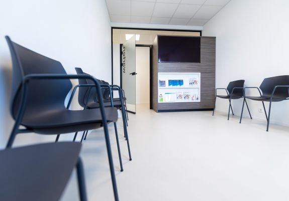 Wartezimmmer mit schwarzen Stühlen und Fernseher